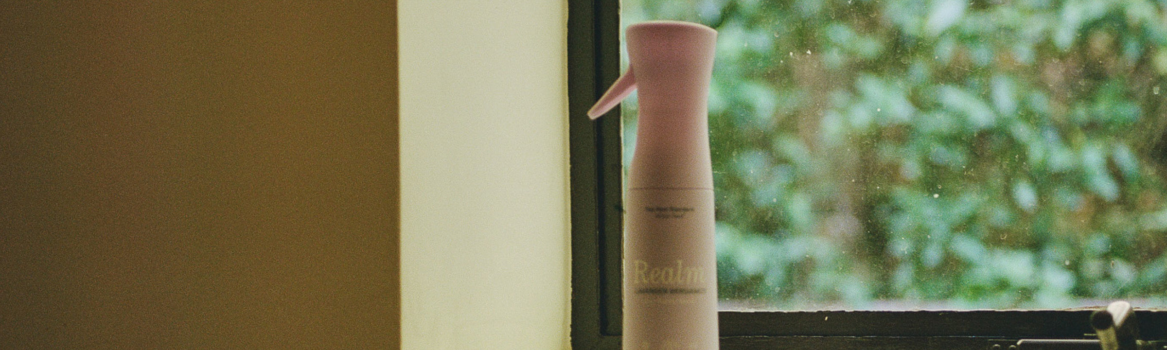 Hair care product with brand name on a window sill with greenery outside